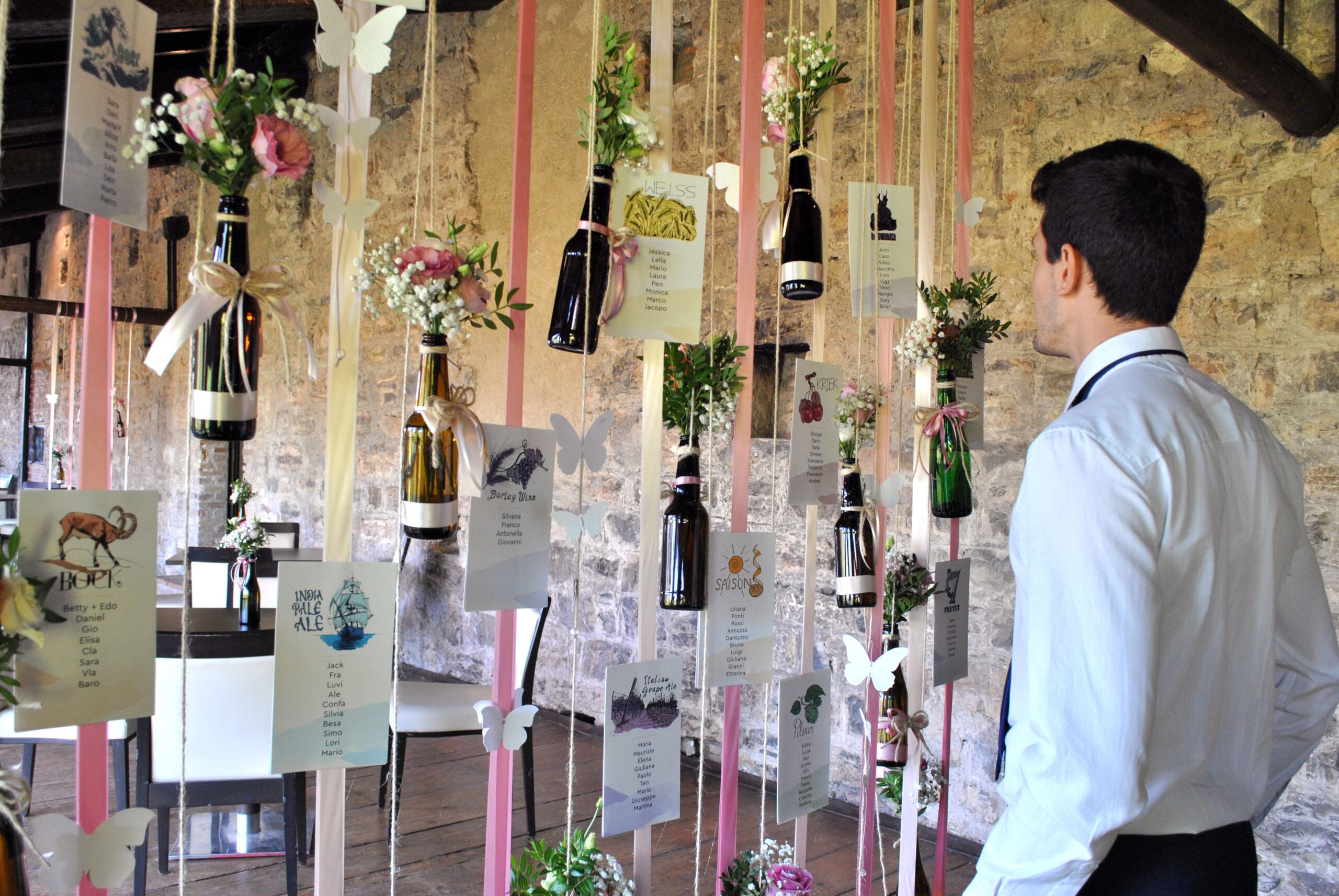 Allestimento per un matrimonio: composizione bottiglie e fiori, card indicazione tavoli